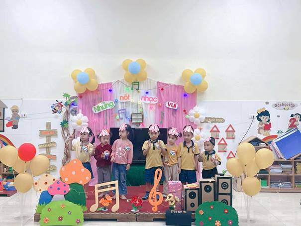 A group of children standing in a room with balloons and a stage

AI-generated content may be incorrect.